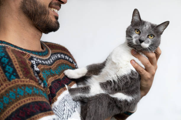 istock Latin American man smiles while holding his cat affectionately in his arms. White background. Pets Concept 1399585560