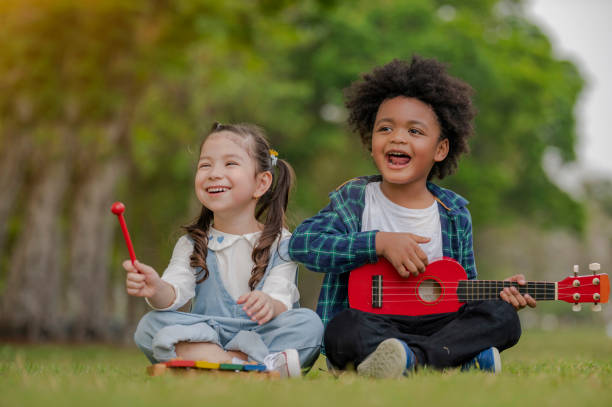 Little girl happiness play with toy block and little boy trying to play with ukulele, kid learning with wooden block and music for education stock photo