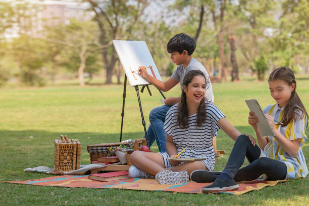 Happy young girl having fun and teasing her friend and a boy enjoys with water colors painting . stock photo