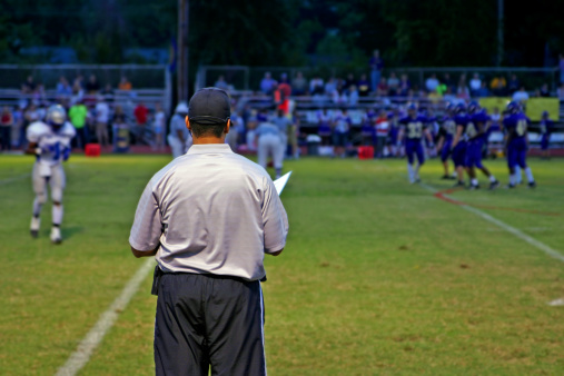 High School football coach watches his team play