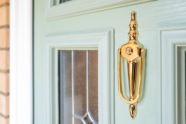 Shallow focus of an ornate door knocker with integrated peep hole. Seen on a newly installed composite double glazed front door. key doormat stock pictures, royalty-free photos & images