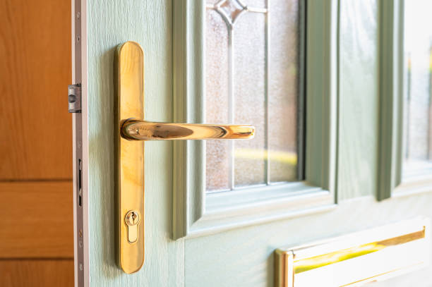 Shallow focus of an ornate, high security door handle and lock seen on a newly installed composite double glazed door Shallow focus of an ornate, high security door handle and lock seen on a newly installed composite double glazed door. Seen ajar and showing part of the hall. key doormat stock pictures, royalty-free photos & images