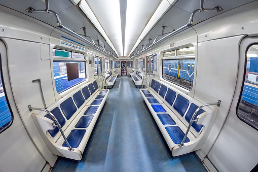 Modern subway metro train inside interior, empty public transport with blue seats. Wagon with open doors in the depot