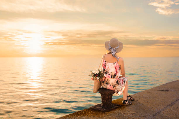 istock Woman relaxing by the seashore at sunset 1399595375