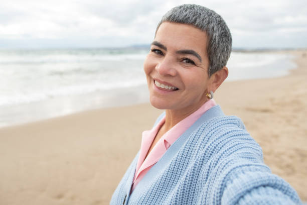istock Cheery senior woman taking selfie at beach 1399595428