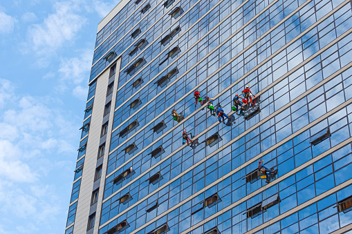 Industrial mountaineering, group of workers cleaning windows service on high rise building. work on the heights