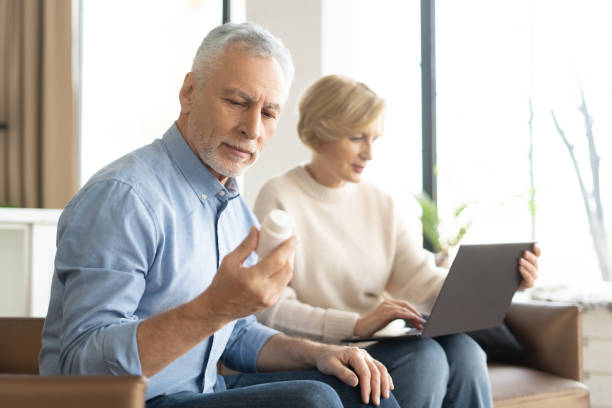 istock Retirement man reading label on pills while his wife checking remedy online 1399601682