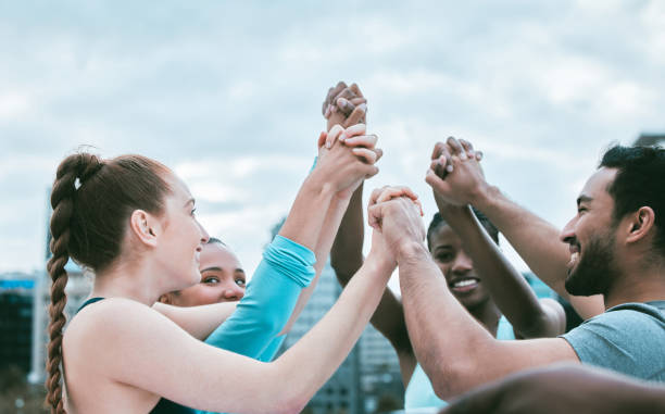 istock Diverse group of people holding hands with arms raised to express unity, support and trust. Motivated athletes cheering while huddled to celebrate winning achievement. Joining together for collaboration and solidarity 1399602668