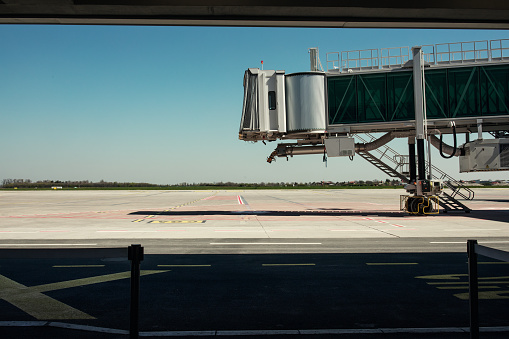 Airport gate with a view on vacant air bridge and apron without airplanes and passengers