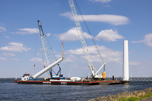 Lelystad, The Netherlands - April 22, 2022: Crane ship and supply vessel busy with demolition old offshore wind turbine