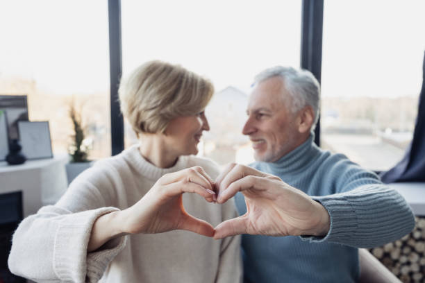 istock Grey haired man and his wife making heart shape gesture 1399604864