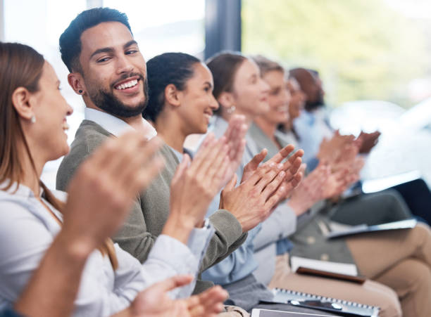 diverse group of smiling businesspeople clapping in office training. team of professional colleagues cheering and celebrating together while learning in workshop. attending a seminar for marketing - training business seminar clapping imagens e fotografias de stock