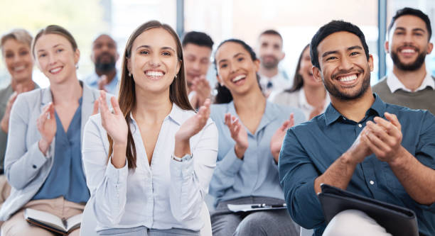 diverse group of smiling businesspeople clapping in office training. team of professional colleagues cheering and celebrating together while learning in workshop. attending a seminar for marketing - training business seminar clapping imagens e fotografias de stock