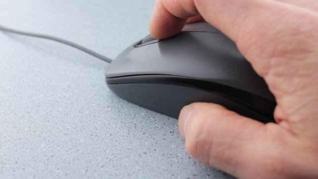 Computer mouse close-up.Computer user uses mouse.Working with laptop computer.Clicking gray computer mouse.
