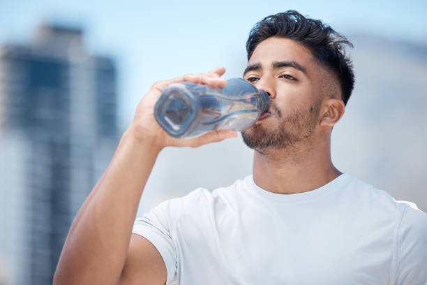 istock Young male athlete taking a break and drinking water from a bottle while out for a run and exercising outdoors during the day 1399607509