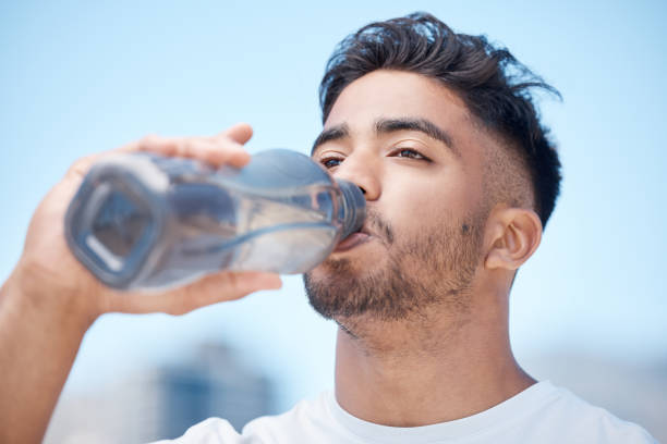 istock Young male athlete taking a break and drinking water from a bottle while out for a run and exercising outdoors during the day 1399607519