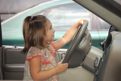 Four year old girl driving a car.
