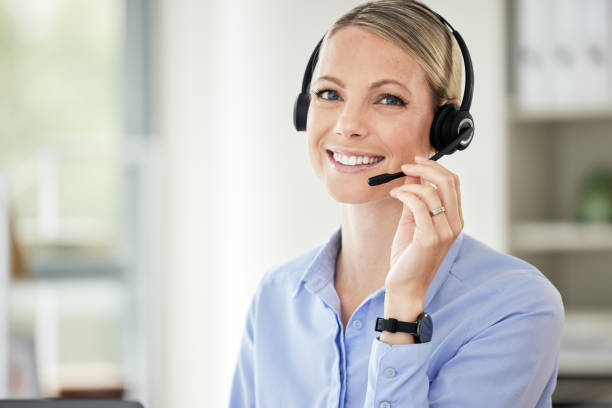 retrato de una joven agente caucásica del centro de llamadas hablando con auriculares mientras trabaja en la computadora en una oficina. mujer de negocios segura y feliz que asesora y opera un servicio de asistencia para ventas al cliente y soporte de ser - bluetooth headset women hands free device fotografías e imágenes de stock