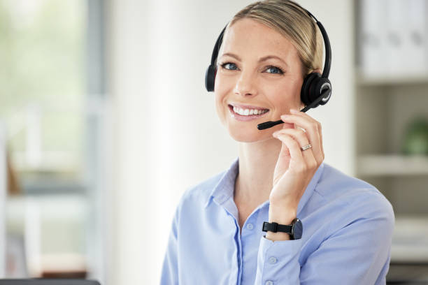 istock Portrait of young caucasian female call centre agent talking on headset while working on computer in an office. Confident and happy businesswoman consulting and operating a helpdesk for customer sales and service support 1399609830