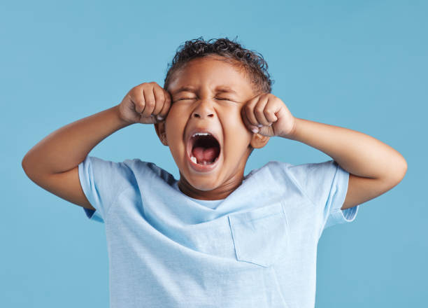 istock Unhappy little hispanic boy looking upset and crying while rubbing his eyes against a blue studio background. Unhappy preschooler kid bawling his eyes out 1399611783