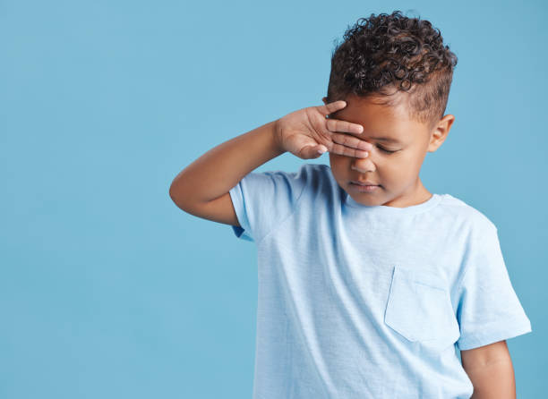 istock Sad little hispanic boy looking sad and rubbing his eyes against a blue studio background. Unhappy preschooler crying on his first day 1399611786
