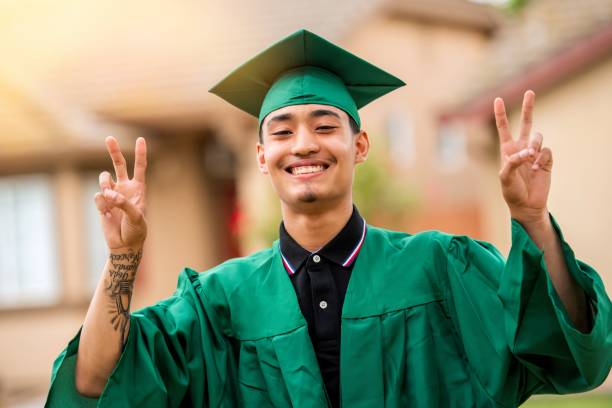 Happy hispanic young men wearing graduation outfit looking at the camera stock photo