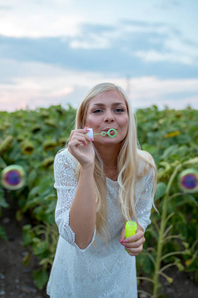 Teenage girl blowing soap bubbles. Indoors, lens flare effect.