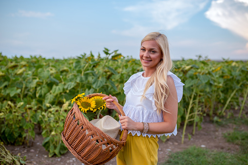 young woman with a straw hat standing in the sunflower field