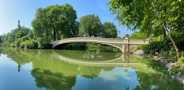 Famous Bow bridge in Central Park is reflected by the surface of the pond.