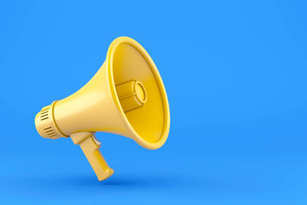 Single yellow electric megaphone with a handle stands on a blue background stock photo