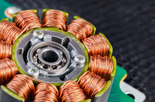 Photo of Electric engine stator with coils copper wire winding or ball bearing on a green PCB detail