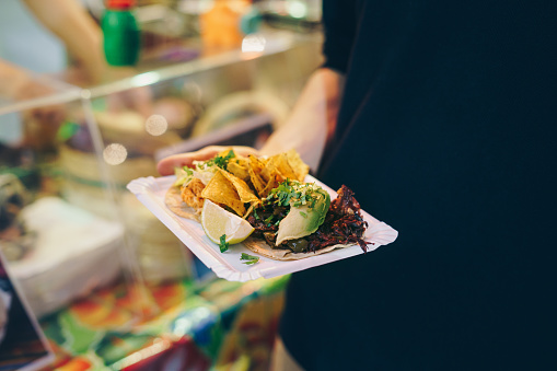 Man eating tacos at a street food market at night