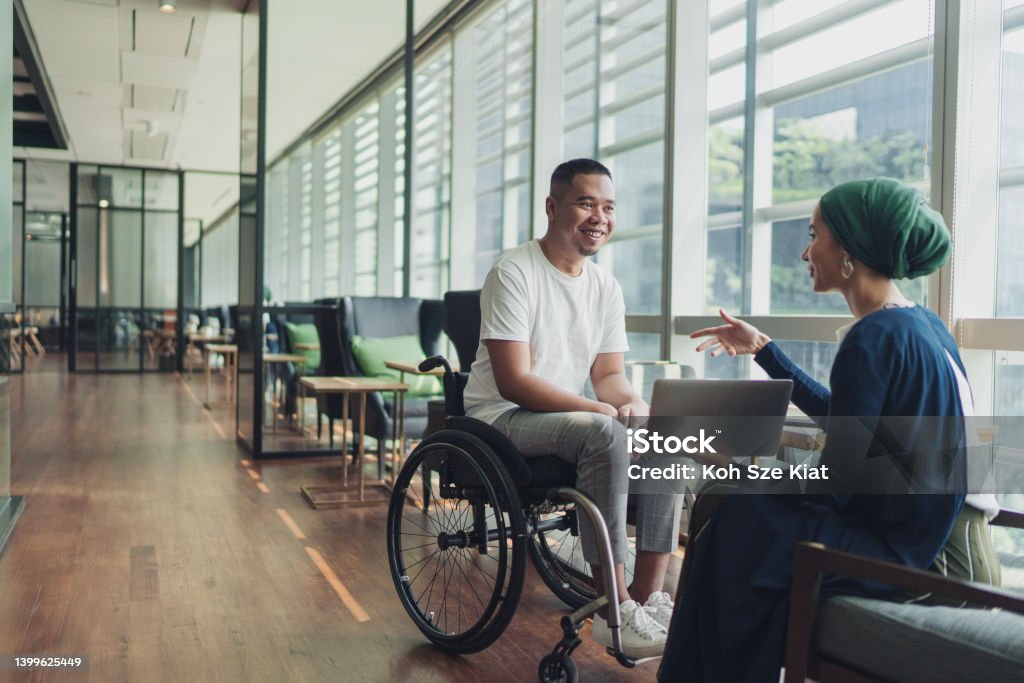 Teamwork in business - A female leader sharing insights with a disabled co worker Diversity Stock Photo