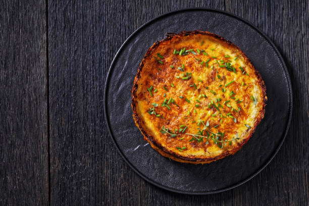 bacon and cheese quiche with hash brown crust Hash Brown crust bacon and cheddar quiche on black plate on dark oak table, horizontal view from above, flat lay, free space, close-up hash brown stock pictures, royalty-free photos & images