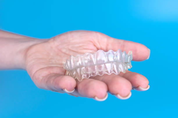 istock Woman holding transparent plastic invisible invisalign retainers on blue background 1399628699