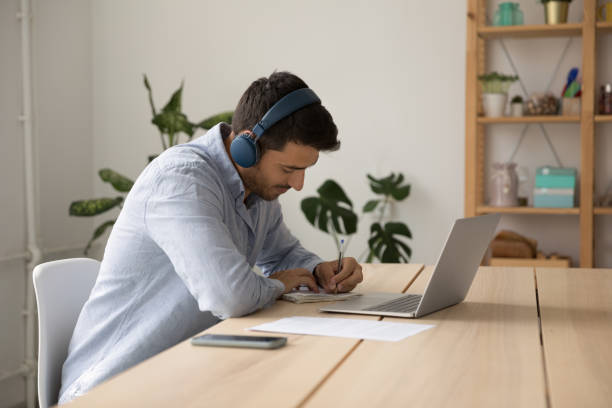 istock Focused young student guy in earphones watching virtual class 1399628853