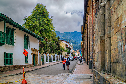 Bogotá, Colombia - January 27, 2017: This is Calle 11 just leaving the Simon Bolivar Square. To the right are the walls of the Catedral Primada and to the left a little bit of the Casa del Florero. In the far background, the Andes Mountains. The altitude at street level is 8,660 feet above mean sea level. Image shot on an overcast afternoon; horizontal format. Copy space.