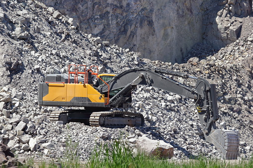 The yellow hydraulic crawler excavator in a stone quarry at work