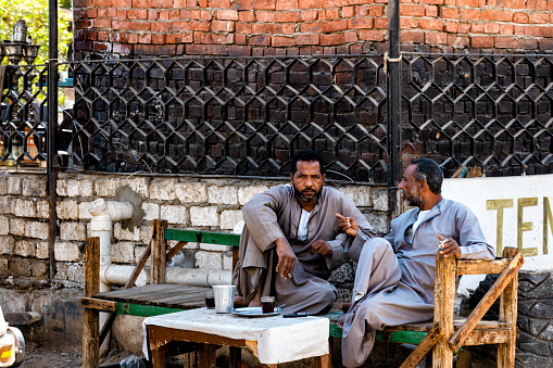 11/6/2019 - Edfu, Egypt - two Egyptian men sitting outside enjoying coffee.