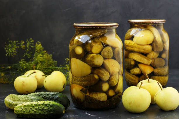 istock Marinated cucumbers with apples in jars are arranged on a dark background, Harvest for the winter, close-up, horizontal photo 1399631962