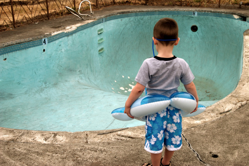 Small Boy Looking at Empty Pool