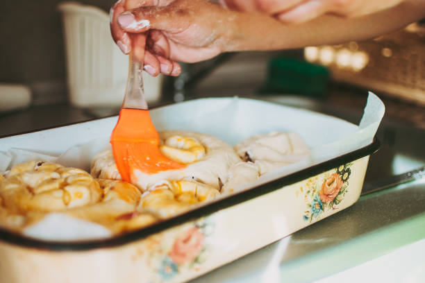 istock Woman spreading egg yolk on casserole dish full of rolls almost ready for baking 1399633868