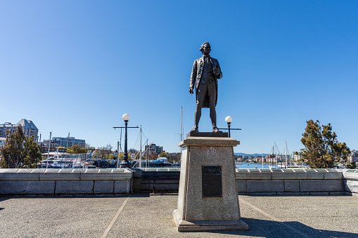 Victoria, BC, Canada - April 14 2021 : Statue of Captain James Cook. Victoria inner harbour causeway.