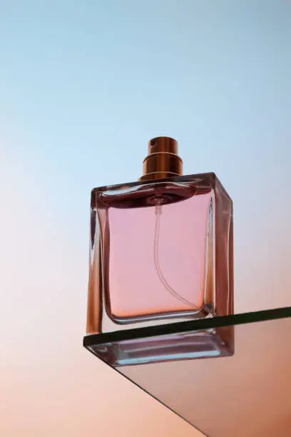 Bottom view of one spray bottle of perfume stands on a glass table.