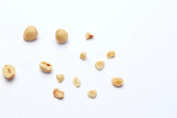 Whole and cracked hazelnuts on the white background with copy space
