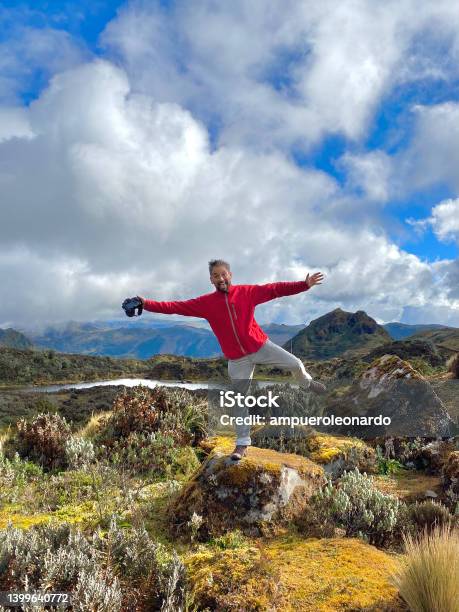 Young Handsome Latin Male Backpacker Photographer Hiking Enjoying And Taking Pictures To The Sierras Highlands In Front Of Pichincha Cayambe And Cotopaxis Volcanoes With A Blue Sky In A Midday Near To Quito Ecuador Stock Photo - Download Image Now