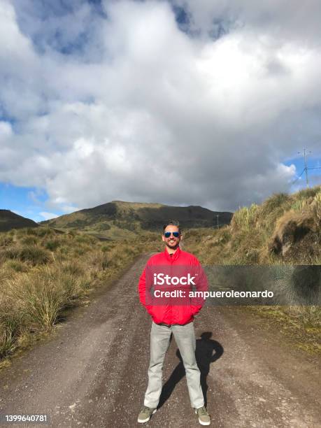 Young Handsome Latin Male Backpacker Hiking And Enjoying His Vacation Time Walking And Hiking On The Sierras Highlands In Front Of Pichincha Cayambe Cotopaxis Volcanoes With A Blue Sky In A Midday Near To Quito Ecuador Stock Photo - Download Image Now