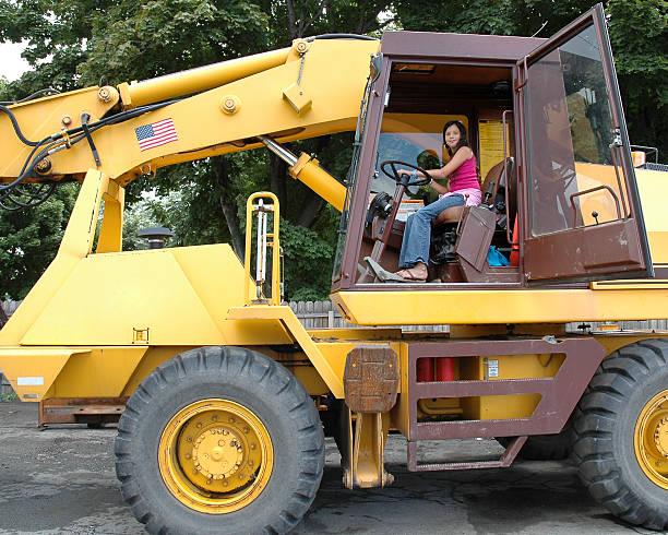 Attractive young girl in the driever's seat of a giant earth mover.