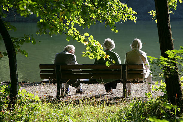Seniors on a park bench Three seniors enjoying the silence on a park bench with view to a lake. senior adult women park bench 70s stock pictures, royalty-free photos & images
