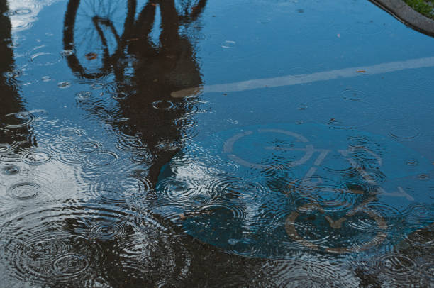 A Viennese bicyclist riding on the sidewalk during a daily rain storm.